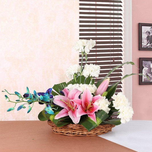 Basket Floral Arrangement like this one. It includes 2 Pink Asiatic Lilies, 10 White Carnations and 2 stems of Blue Orchid